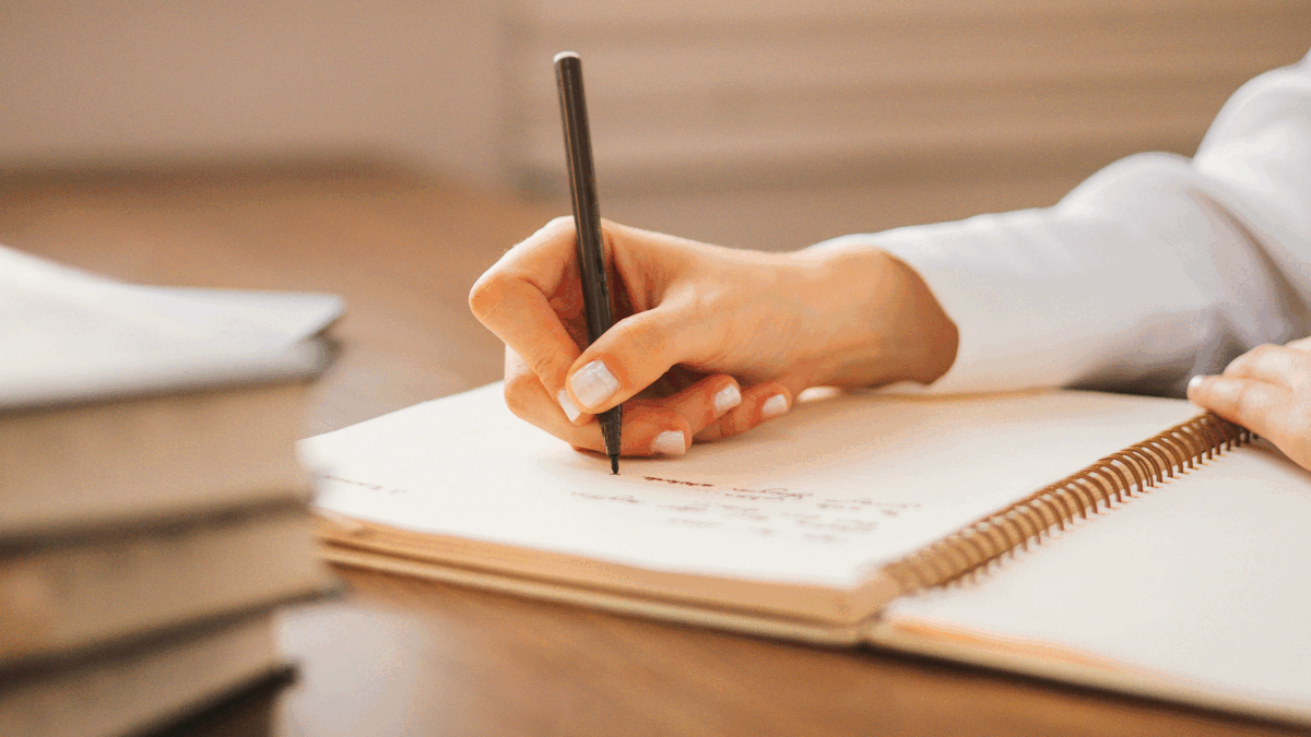 Imagem de uma pessoa escrevendo em um caderno