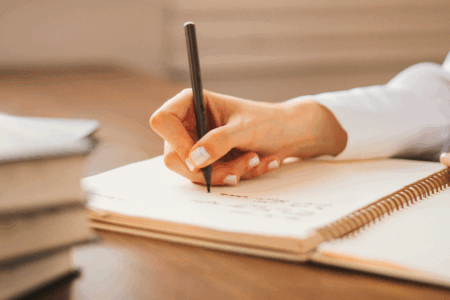 Imagem de uma pessoa escrevendo em um caderno