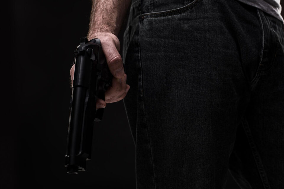 Enquadramento colorido mostra mão masculina com pistola em punho