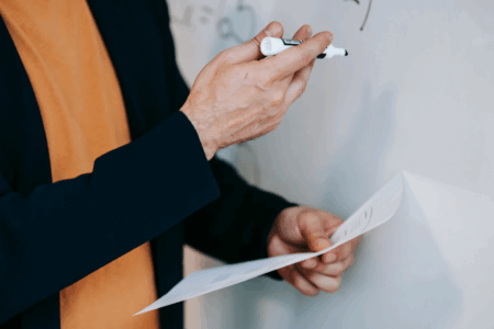 Imagem de um professor segurando um papel e um canetão