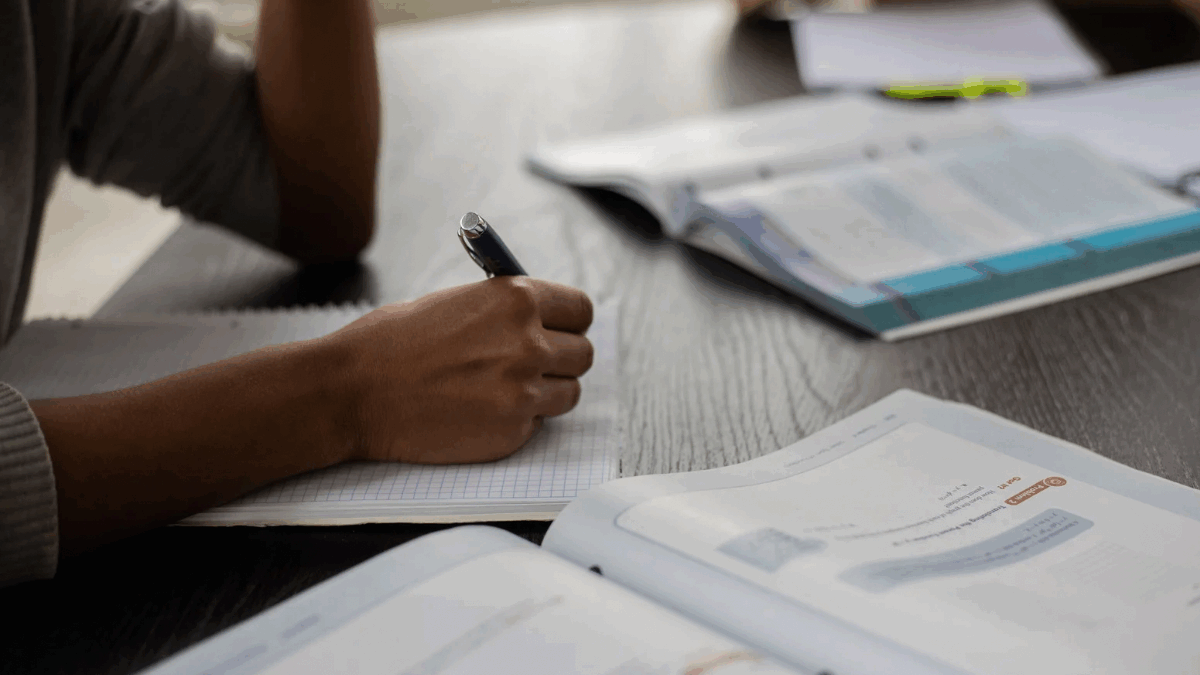Imagem de uma pessoa estudando com cadernos e livros