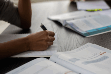 Imagem de uma pessoa estudando com cadernos e livros