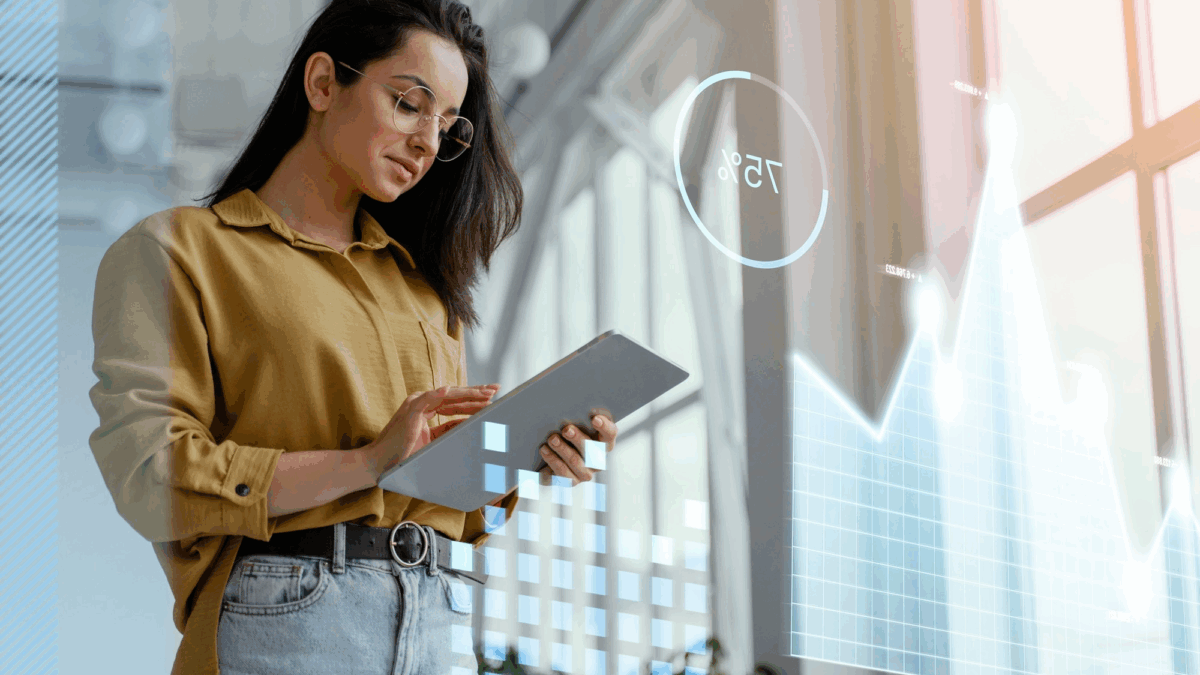 Mulher jovem, de cabelos compridos segura um tablet diante de uma imagem tecnológica. Ela olha diretamente para o aparelho