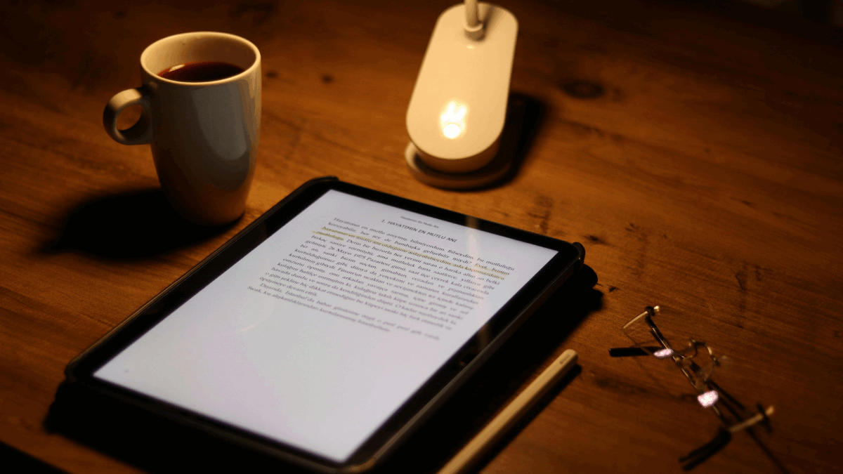 Imagem de um kindle ao lado de uma caneca de café