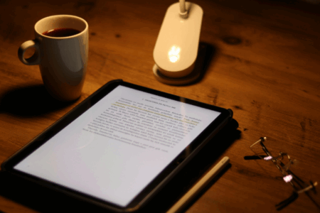 Imagem de um kindle ao lado de uma caneca de café