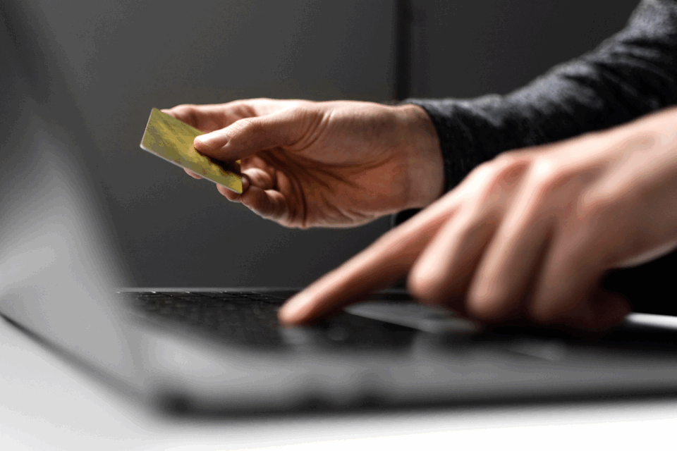 Homem com cartão de crédito no computador
