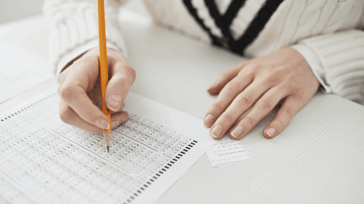 Imagem de uma pessoa preenchendo o gabarito de uma prova