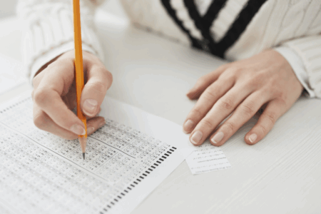 Imagem de uma pessoa preenchendo o gabarito de uma prova