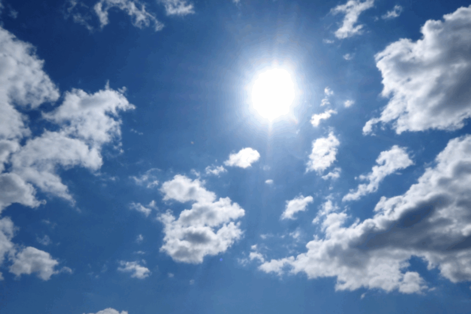 Imagem de um céu com nuvens e um sol radiante