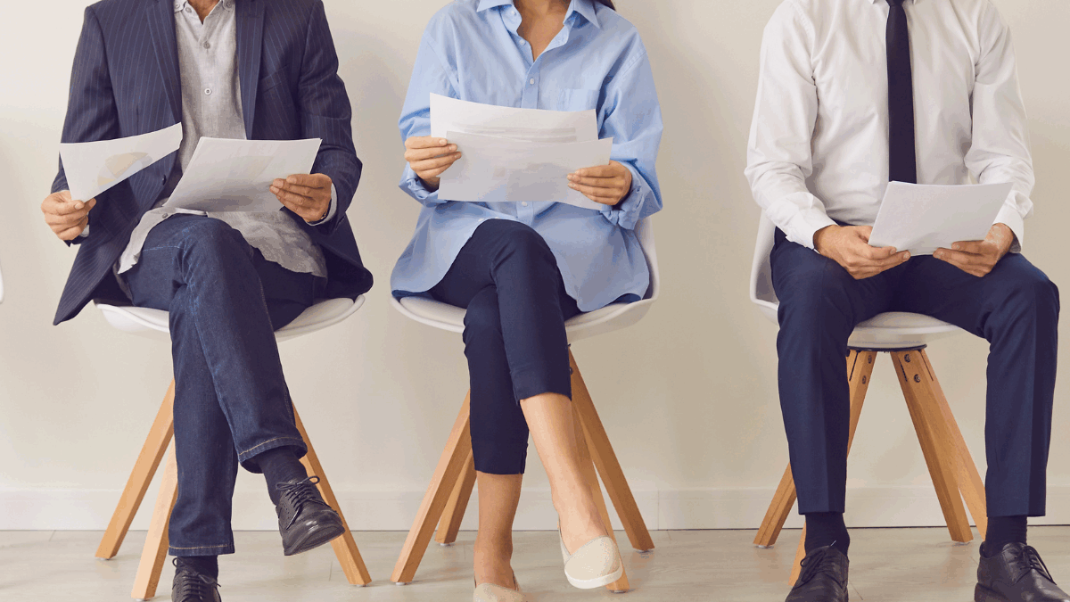Imagem de pessoas segurando currículos, esperando serem chamadas para a entrevista de emprego