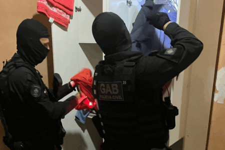 Imagem de policiais fazendo buscas em uma casa