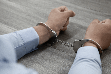 Imagem de um homem com algemas nos pulsos
