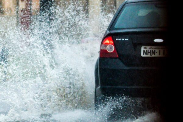Imagem mostra carro trafegando por via alagada em Goiânia