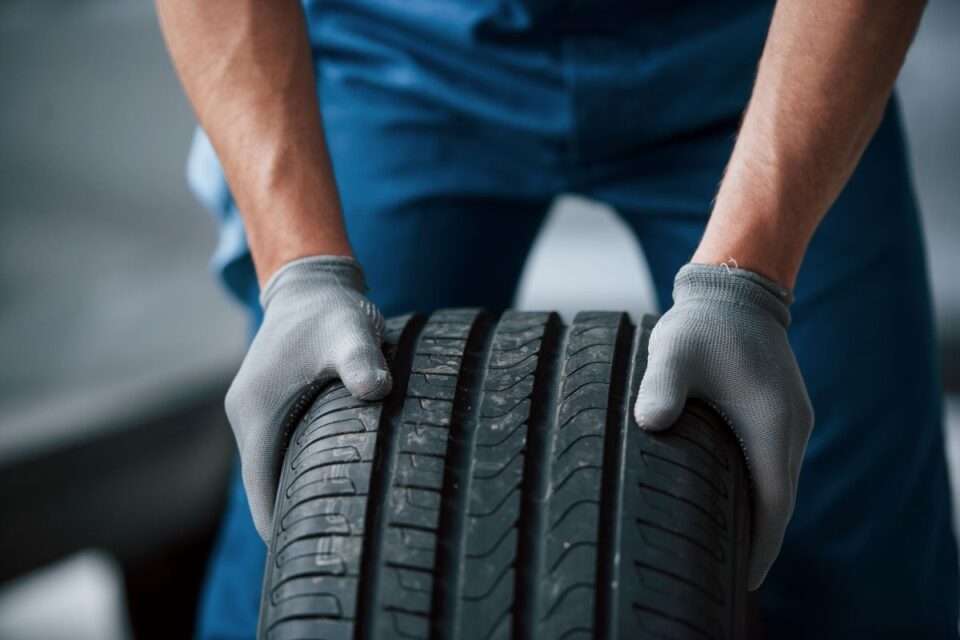 sujeira-na-roda-mecanico-segurando-um-pneu-na-oficina-substituicao-de-pneus-de-inverno-e-verao