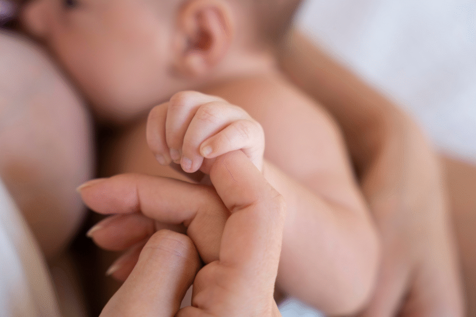 Bebê recém-nascido segura a mão da mãe