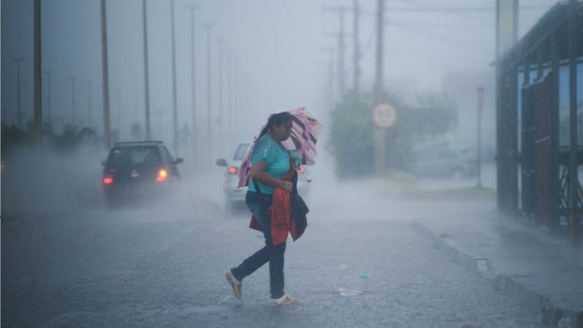 Imagem mostra mulher atravessando rua em meio a chuva forte