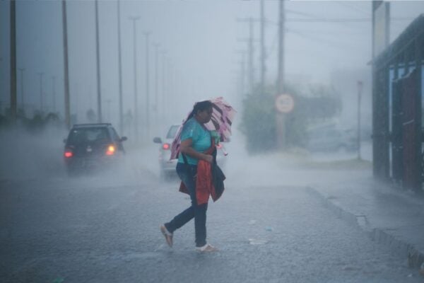Imagem mostra mulher atravessando rua em meio a chuva forte