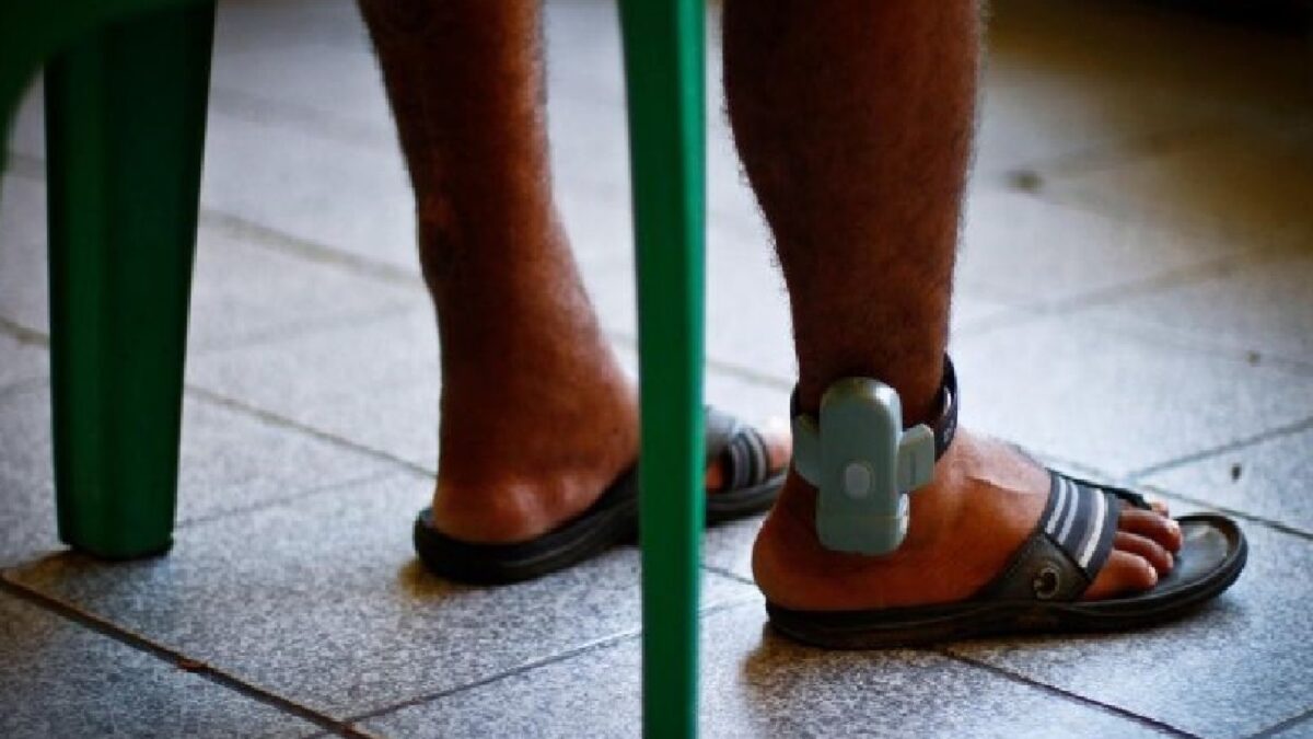 Imagem mostra homem com monitoramento eletrônico no pé direito