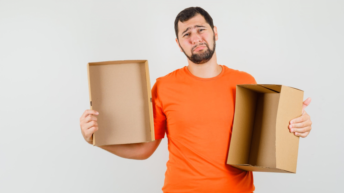 Homem triste com uma camiseta laranja segura uma caixa vazia