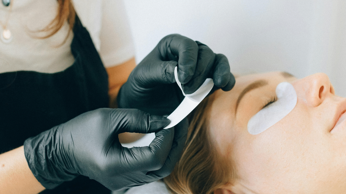 Imagem de uma mulher realizando extensão de cílios em cliente