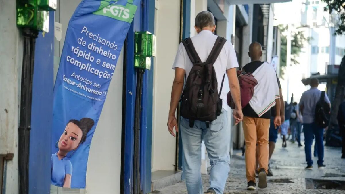 Imagem mostra trabalhadores caminhando em calçada movimentada