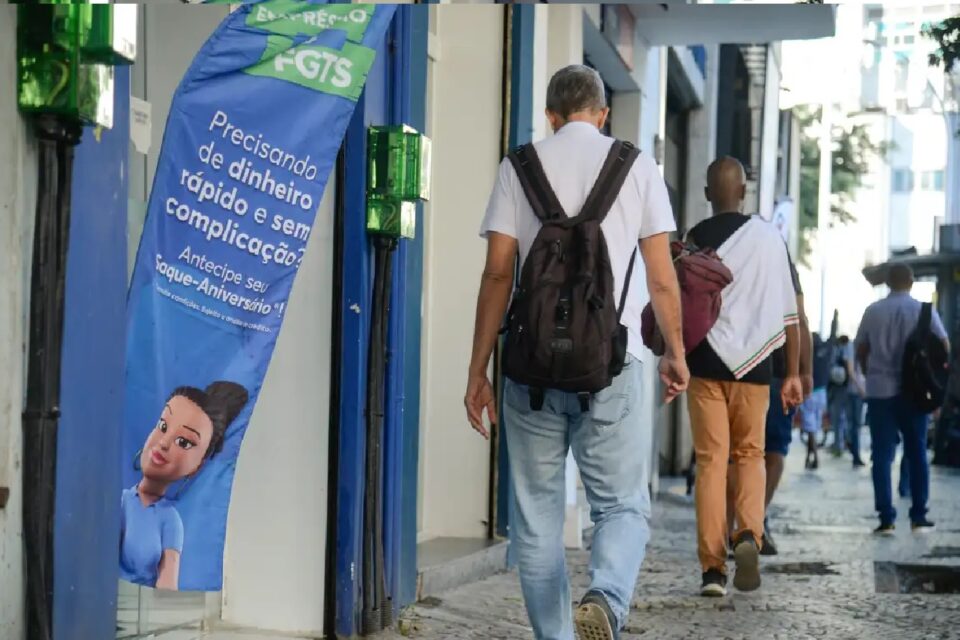 Imagem mostra trabalhadores caminhando em calçada movimentada