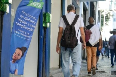 Imagem mostra trabalhadores transitando por calçada