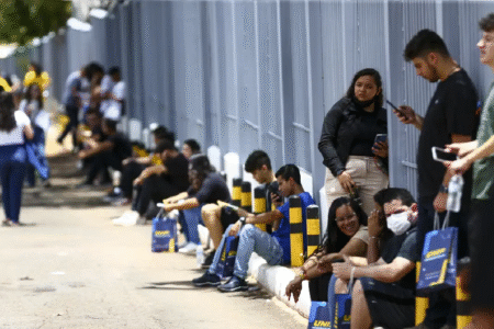 Imgem mostra estudantes aguardando abertura dos portões