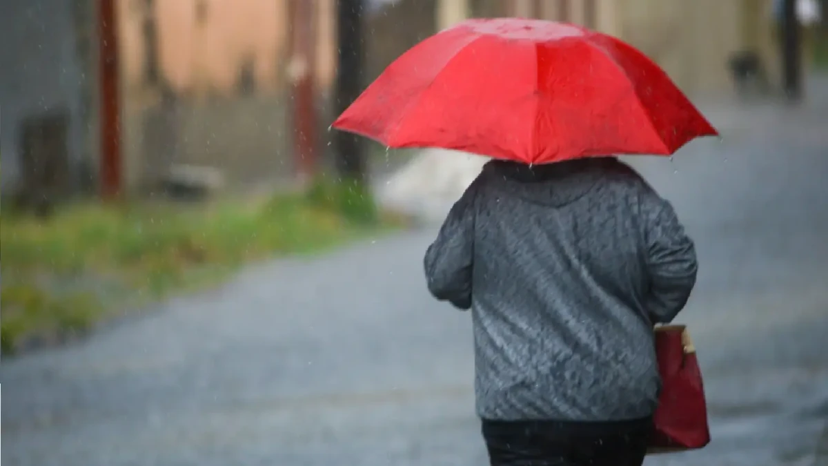 Imagem mostra pedestre transitando durante chuva