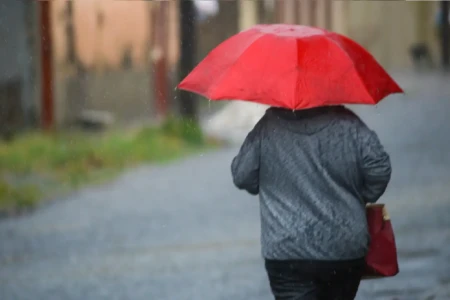 Imagem mostra pedestre transitando durante chuva