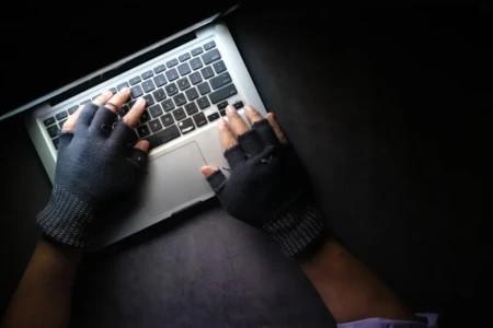 Imagem de uma pessoa mexendo no notebook no escuro