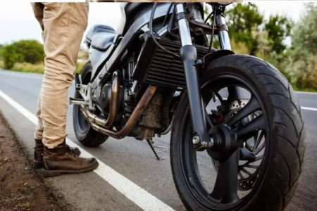 Imagem mostra homem ao lado de motocicleta no acostamento de uma rodovia