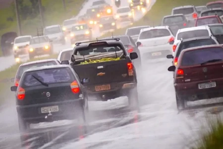 Imagem mostra veículos transitando em rodovia em meio à chuva