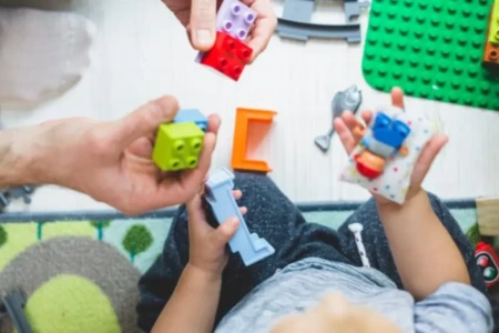 Imagem de uma criança brincando com auxílio de um adulto