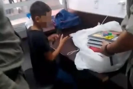 Garoto recebendo material escolar doado pela PM (Foto: reprodução/PMGO)