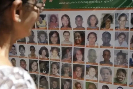 Imagem mostra mulher analisando retratos de pessoas desaparecidas