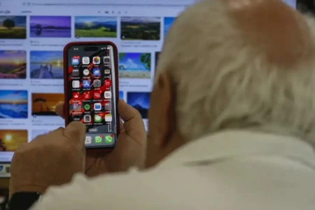 Imagem mostra idoso utilizando telefone celular