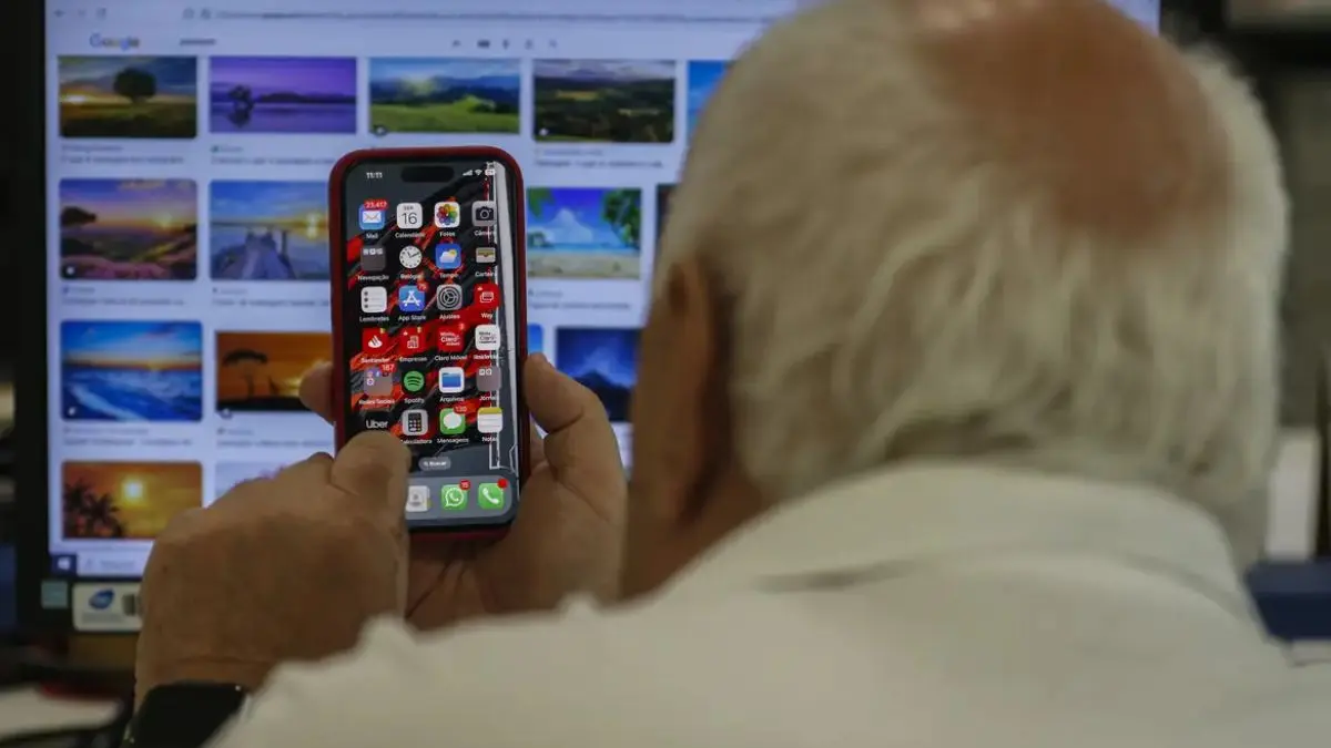 Imagem mostra idoso utilizando telefone celular