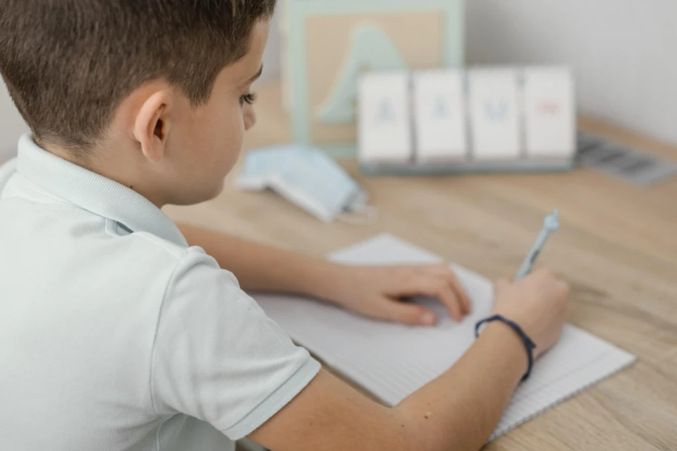 Menino estuda frente a uma mesa