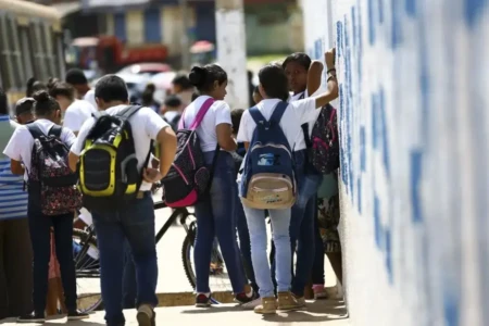 Imagem mostra alunos em frente a colégio estadual
