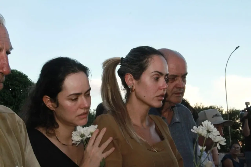 Mulher ampara outra mulher que chora. Ao lado de um homem idoso.