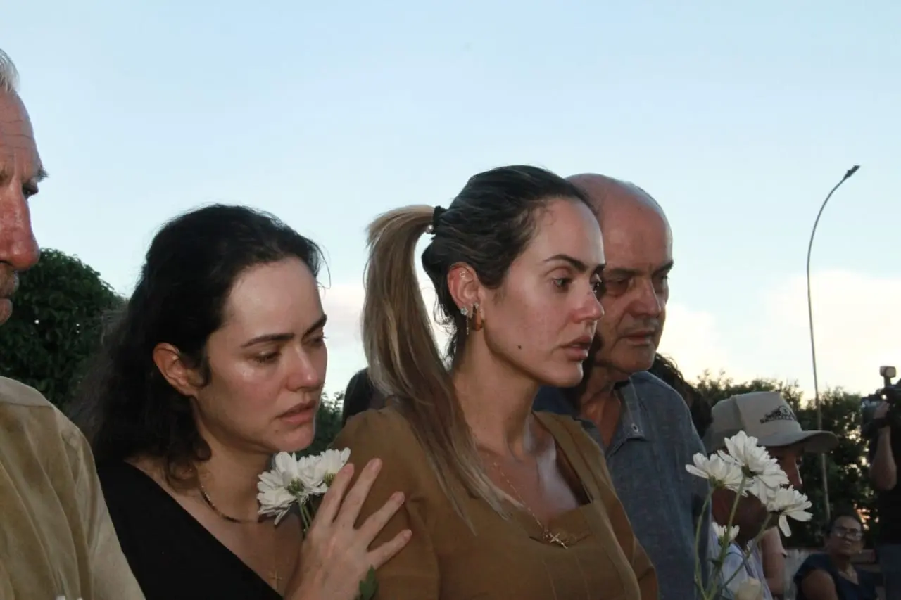 Mulher ampara outra mulher que chora. Ao lado de um homem idoso.