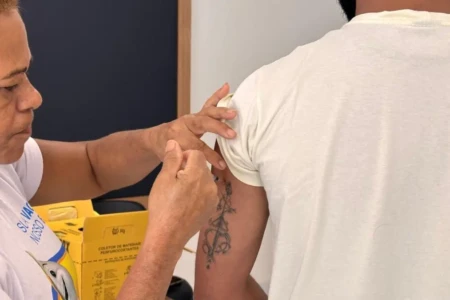 Imagem mostra trabalhador da linha de frente recebendo dose aplicada pela SMS