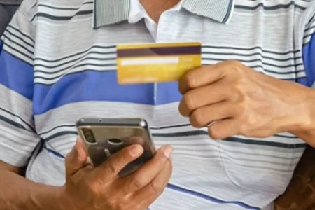 Imagem mostra homem consultado dados do cartão durante uso do celular