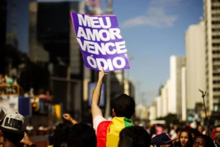 Imagem mostra ativista com placa escrita : "meu amor vence o ódio"