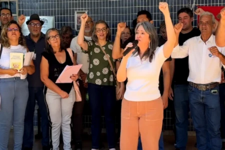 Pessoas em frente a uma unidade de saúde fazendo manifestação