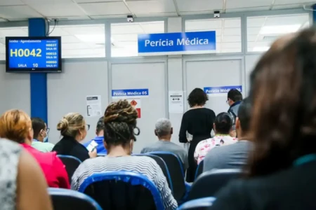 Pessoas de costas aguardando atendimento na perícia médica do INSS