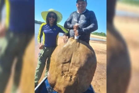 Pescadora Eliete Ribeiro ao lado do marido e da arraia gigante - (Foto: reprodução/arquivo pessoal)
