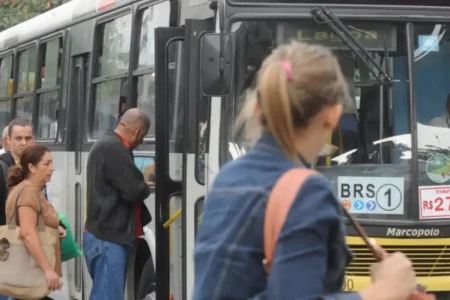 Imagem mostra mulher prestes a embarcar em ônibus do transporte coletivo