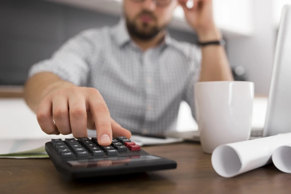 Destaque da mão de um homem com a mão na calculadora